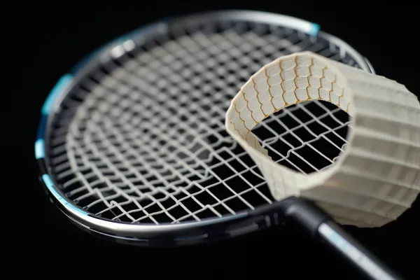 Cận cảnh cây vợt cầu lông cắt đôi, lộ rõ lõi giấy tổ ong (Nomex core) bên trong, nền tối, ánh sáng nhấn.