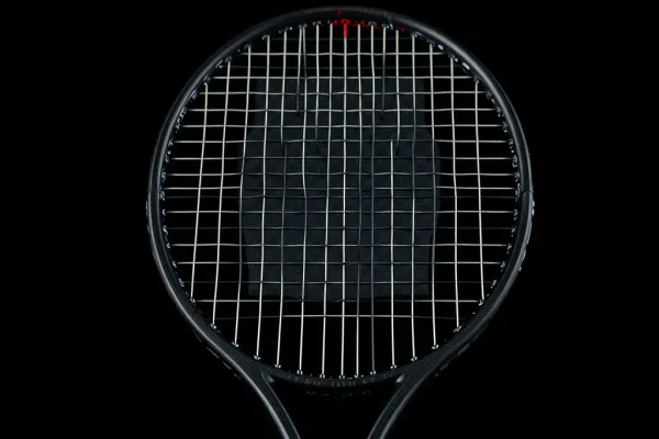 Mặt vợt tennis làm từ carbon 3K với kết cấu sợi tổ ong rõ rệt, được chiếu sáng studio trên nền tối, góc cận cảnh chất liệu