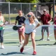 Những người mới chơi pickleball đang đánh bóng bằng vợt trên sân ngoài trời, vui vẻ và dễ học, phù hợp với hướng dẫn nhanh.
